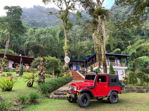 a red jeep parked in front of a house at FINCA HOTEL CARMONIA DEL BOSQUE in Venecia