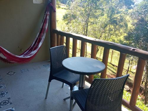 a table and two chairs on a balcony with a view at Recanto Berço das Aguas in Piraquara