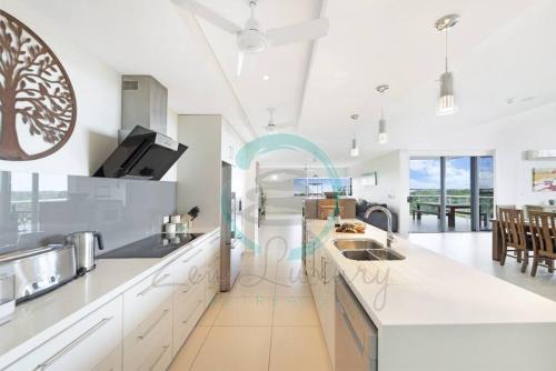 a kitchen with white countertops and a dining room at ZEN LUXURY: 2-Story 4-BR Penthouse in Darwin City with Mindal Markets & Harbour Views in Darwin