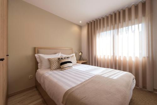 a bedroom with a large bed and a window at Oliva Welcoming Apartments in Proença-a-Nova