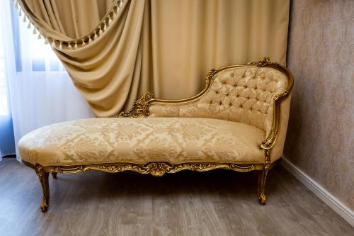 a gold couch sitting in front of a curtain at Grand Hotel Baroc in Zalău