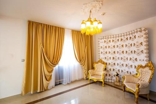 a living room with two chairs and a chandelier at Grand Hotel Baroc in Zalău