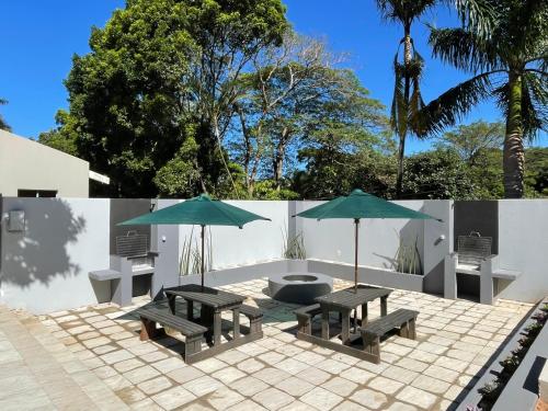 - deux tables de pique-nique et deux parasols sur la terrasse dans l'établissement Guest house on Gillian Unit 4, à Ballito