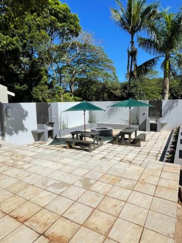 a patio with picnic tables and umbrellas at Guest house on Gillian Unit 5 in Ballito