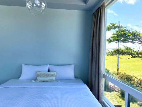 a blue bedroom with a bed and a window at 墾丁花見小院Villa包棟民宿 in Eluan