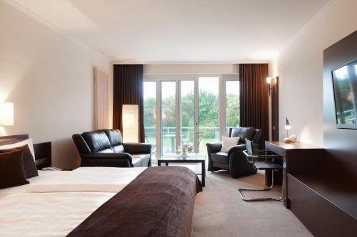 ein Hotelzimmer mit einem Bett und Stühlen in der Unterkunft nordica Hotel Berlin in Heide