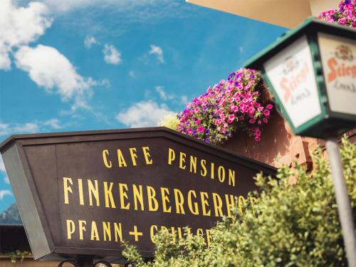 a sign in front of a building with flowers at Hotel Finkenbergerhof in Finkenberg