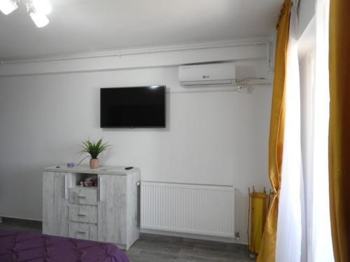 een woonkamer met een tv aan een witte muur bij Garsoniera in Năvodari