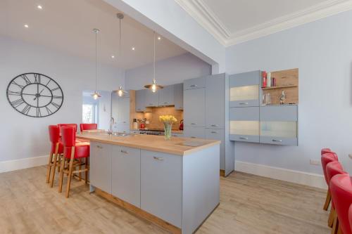 a kitchen with white cabinets and red chairs at Carlton House Portpatrick in Portpatrick