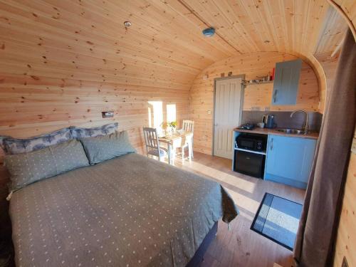 a bedroom with a bed in a wooden cabin at Rowan - Luxury Pod at Trewithen Farm Glamping in Launceston