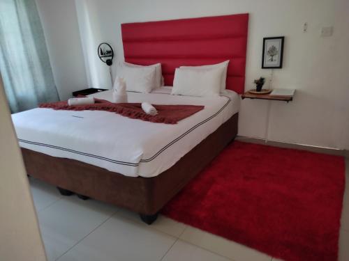a bedroom with a large bed with a red headboard at Shalakwe Hills-Inn Guesthouse Kasane in Kasane