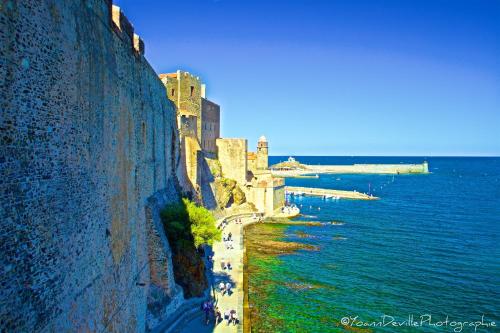 a castle on the side of a cliff next to the water at The Originals City, Hôtel Les Dômes, Perpignan Sud Saleilles in Perpignan