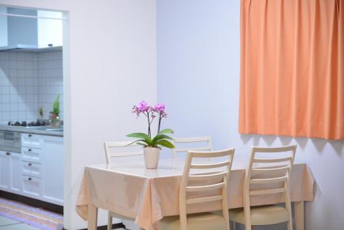 a dining room table with a vase of flowers on it at Kanae House in Tokyo