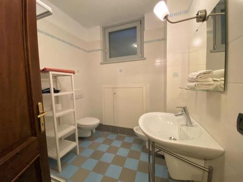 a white bathroom with a sink and a toilet at San Sisinio Apartment Argegno in Argegno