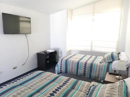 1 dormitorio con 2 camas y TV en la pared en Andina Lodge, en Arequipa