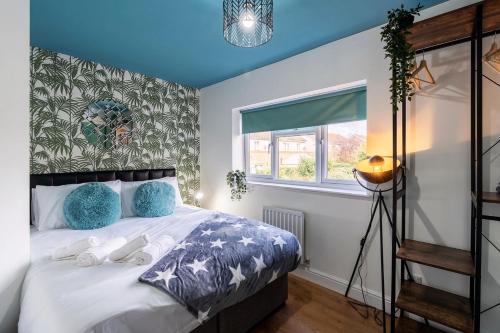 a bedroom with a bed with blue pillows and a window at Large Contractor and Family House & Free Parking & Big Garden in Hull