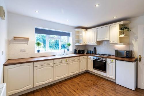 a kitchen with white cabinets and a window at Large Contractor and Family House & Free Parking & Big Garden in Hull