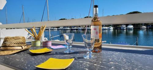 une bouteille de vin posée sur une table avec des verres dans l'établissement Marina Lairan Vue sur l'eau et les bateaux de Port Camargue 2étoiles F, au Grau-du-Roi