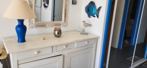 a white dresser with a blue lamp and a mirror at Marina Lairan Vue sur l'eau et les bateaux de Port Camargue 2 étoiles F in Le Grau-du-Roi