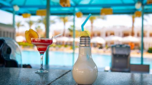 a bottle and a drink on a table near a pool at Happy Life Village Dahab in Dahab