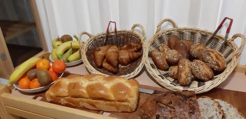 three baskets of different types of bread and fruit on a table at Logis hôtel restaurant le relais de l'abbaye in Saint-Évroult-Notre-Dame-du-Bois