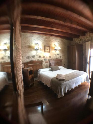 a bedroom with a large bed and a stone wall at Hospederia Casa de Cisneros in Toledo