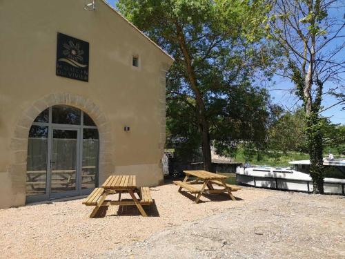 two picnic tables in front of a building at LE MOULIN DU VIVIER in Saint-Martin-Lalande