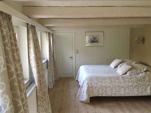 1 dormitorio con cama blanca y ventana en Höllenmühle Bed & Breakfast at the Mill Pond, en Hessisch Oldendorf
