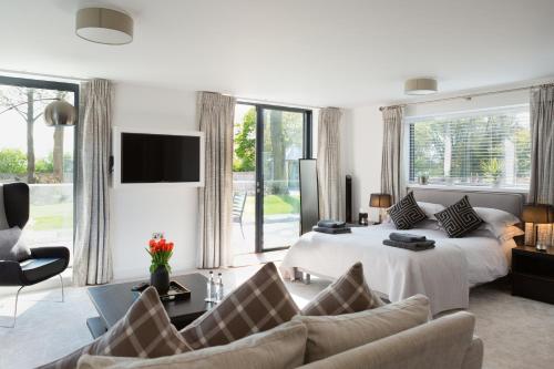 a white bedroom with a bed and a living room at Dafarn Newydd Studio in Llangefni