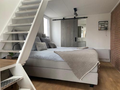 a bedroom with a white bed and a staircase at Logeren bij Grea in Zwartsluis