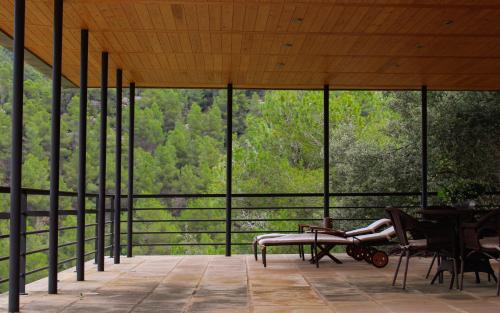 a woman laying on a chair on a porch with a view of trees at Torre del Marqués Hotel Spa & Winery - Small Luxury Hotels in Monroyo