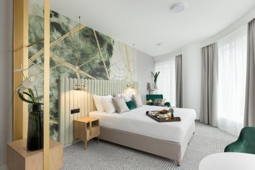 een slaapkamer met een wit bed en een groot schilderij aan de muur bij Royal Tulip Warsaw Apartments in Warschau