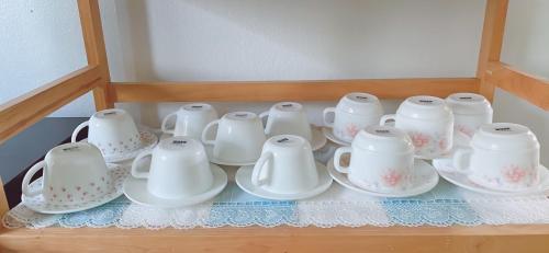 a group of white cups and saucers on a shelf at Sea Hill Sattahip in Sattahip