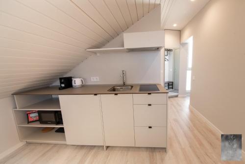 an attic kitchen with white cabinets and a sink at COME2rest - Smilga in Juodkrantė
