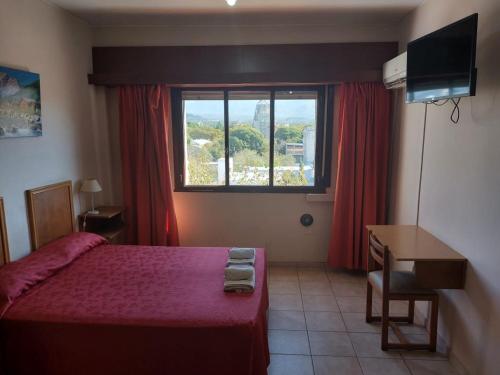 a bedroom with a bed and a desk and a window at Hotel El Torreon in Mendoza