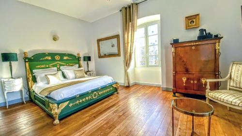 a bedroom with a green bed and a chair at Domaine de Monplaisir in Caylus