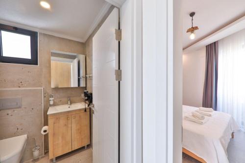een badkamer met een bed, een wastafel en een spiegel bij Happy Kaş Apart in Kas