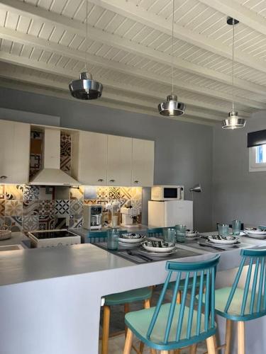 a kitchen with two blue chairs and a counter at Θἔρως (Theros) house 3- Agios Fokas in Agios Sostis