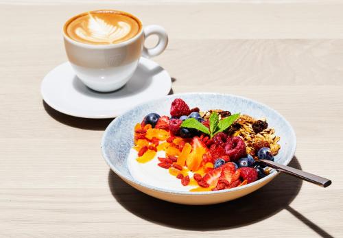 un tazón de cereales y fruta junto a una taza de café en Century City Hotel Bridgewater, en Ciudad del Cabo