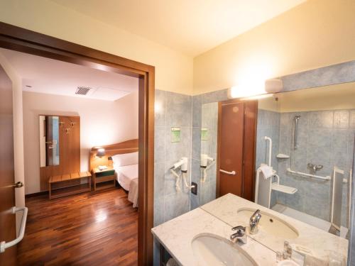 baño con lavabo y habitación con cama en Hotel Il Duca d'Este, en Ferrara