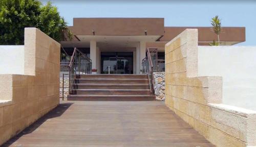 a building with a wooden walkway in front of it at Anavadia Hotel-All Inclusive in Kolimbia