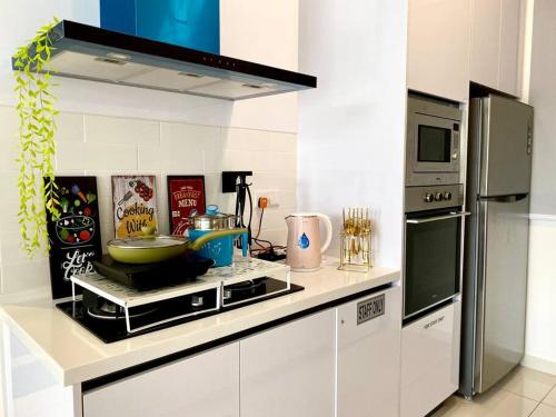a kitchen with a stove top oven next to a refrigerator at Beacon Executive Suite by stayCATion Homestay in George Town