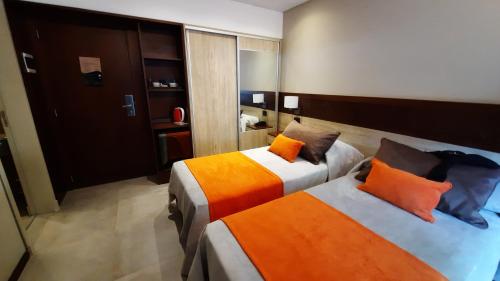 a hotel room with two beds with orange pillows at Hotel Estilo MB - Merlo in El Rincón