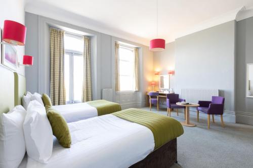 a hotel room with two beds and a table and chairs at The Caledonian New Southlands Hotel in Scarborough
