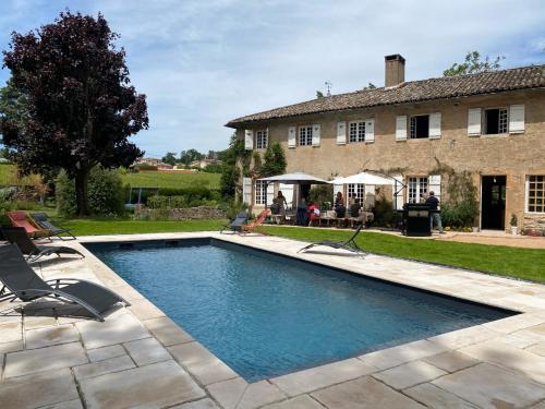 uma piscina com cadeiras e uma casa em LE GITE DU CARGE D'ARLAY em Charnay-lès-Mâcon