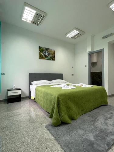 a bedroom with a large bed with a green blanket at Apartman Nikolic 2 in Teslić