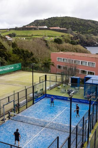 three people playing tennis on a tennis court at Terceira Mar Hotel in Angra do Heroísmo