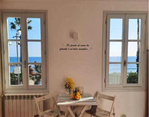 a dining room with a table and two windows at Finestre sul Mare in San Lorenzo al Mare