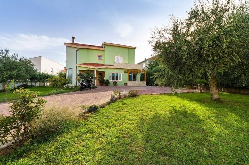 a green house with a driveway and a yard at Apartmani Vanja in Zadar