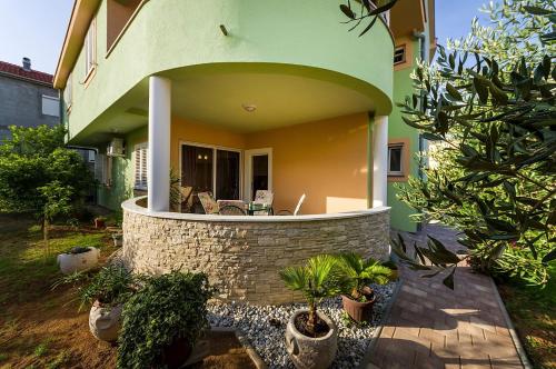 a house with a green and yellow building with plants at Apartmani Vanja in Zadar